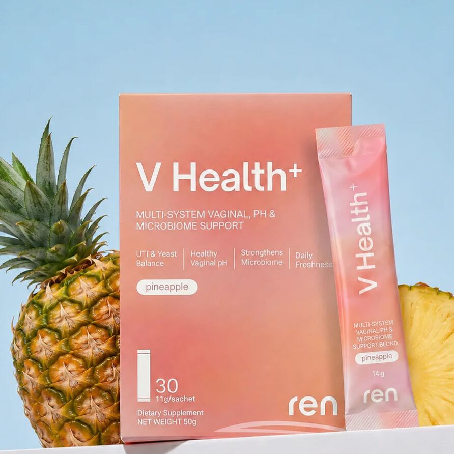 Studio product shot of a supplement box and single-serve sachet styled with fresh pineapple against a pale blue background